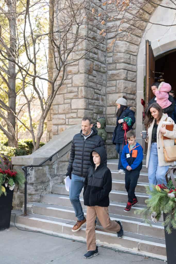 Family exiting Brookside Campus church. People walking down stone steps, dressed in winter coats.