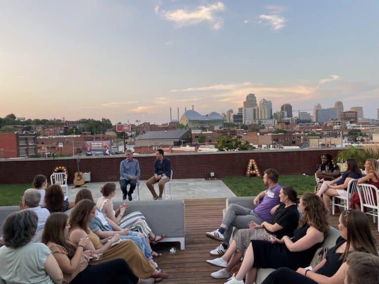 Outdoor event on a rooftop in downtown Kansas City, with speakers and audience. City skyline in the background.