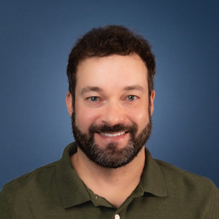 Headshot of Matt Wadsworth smiling against a blue background.