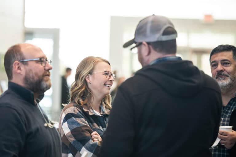Group of people talking, possibly about a new home, at a Christ Community Church event.