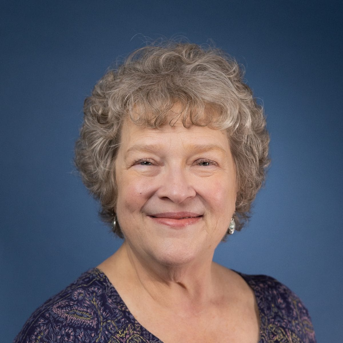 Headshot of Cecilia Riegel smiling against a blue background.